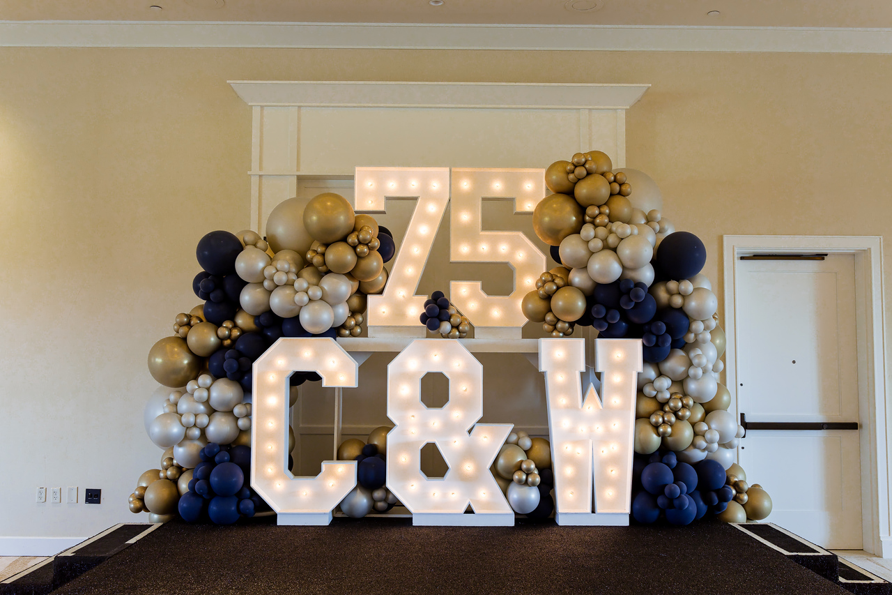 75th Anniversary display featuring gold balloons and event branding at Cummins & White’s celebration.